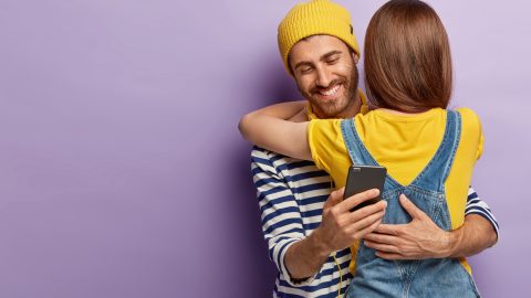 Man secretly texting while hugging