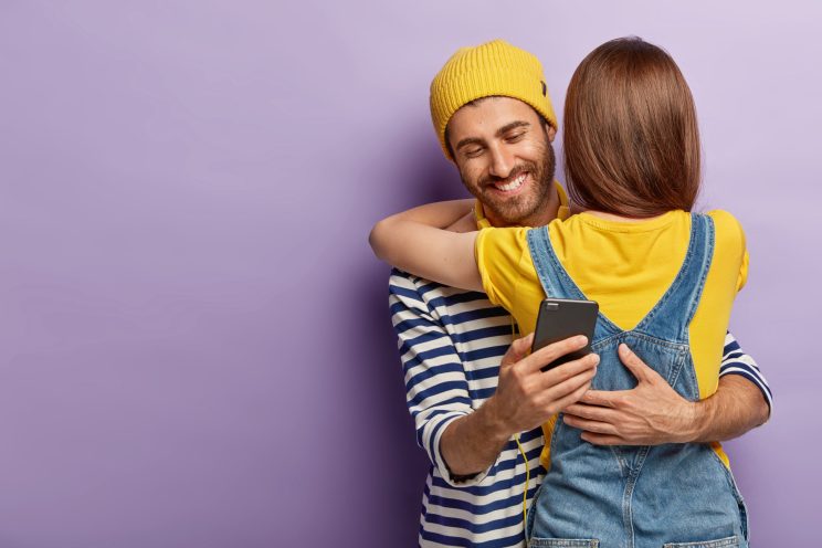 Man secretly texting while hugging