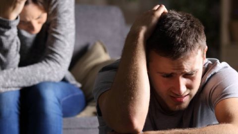 A distraught man sitting alone, deep in thought, grappling with the challenge of surviving infidelity.