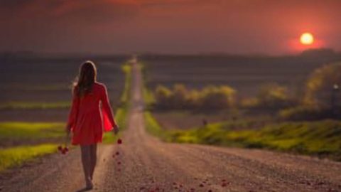 A solitary woman walking away on a path, symbolizing the difficult decision to move on after infidelity.
