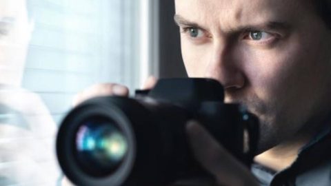 Private investigator discreetly holding a camera during surveillance operations, raising the question: are private investigators legal?