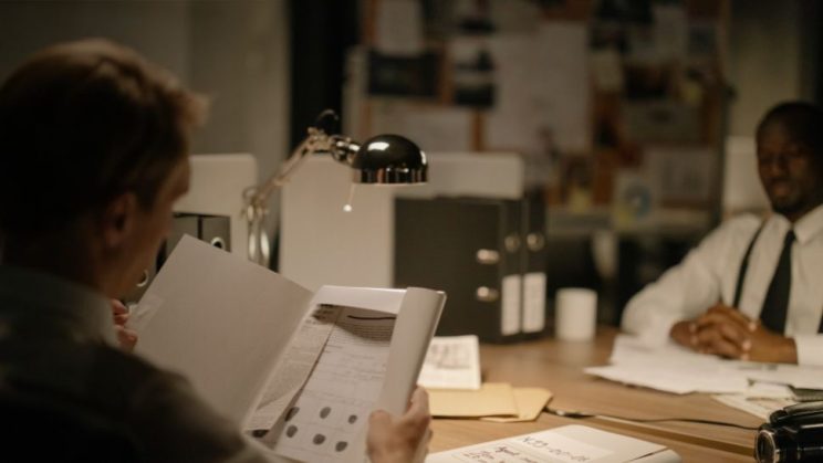 Detective analyzing case files and evidence on a board in an office