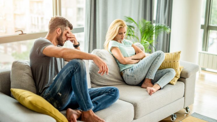 A couple sitting on a sofa, deep in thought.