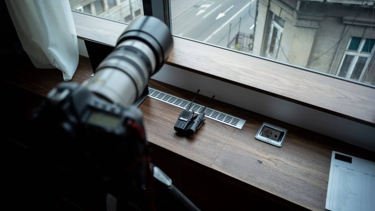 Private investigator in a car taking surveillance photos through a window