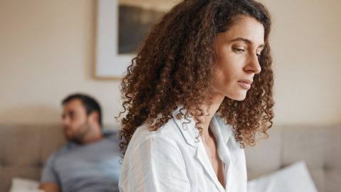 Woman sitting on bed with her partner, symbolizing rebuilding a relationship after emotional cheating