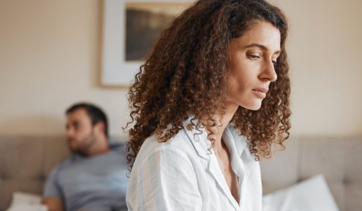 Woman sitting on bed with her partner, symbolizing rebuilding a relationship after emotional cheating
