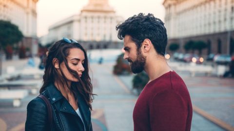 A man and woman standing face to face outdoors