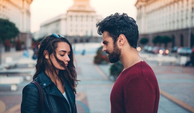 A man and woman standing face to face outdoors