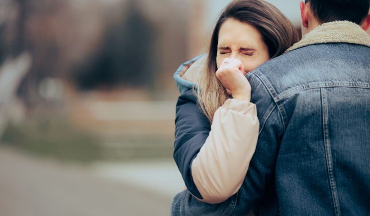 A woman tightly hugging a man with eyes closed