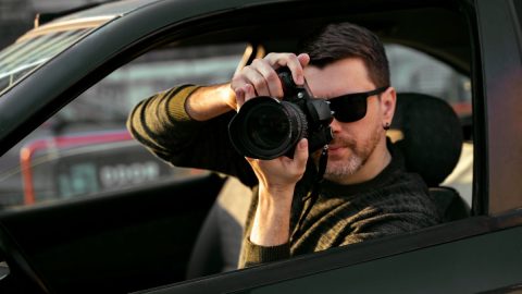 Private investigator taking photos from a car window
