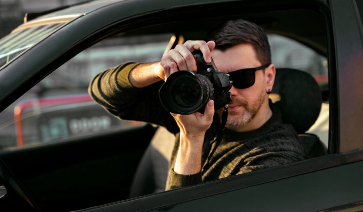 Private investigator taking photos from a car window