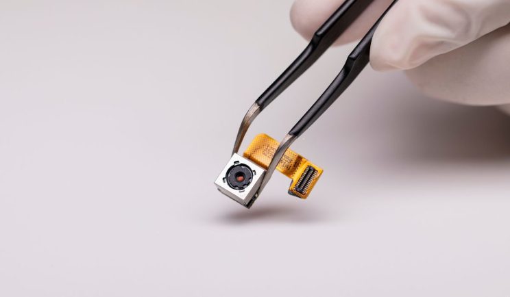Close-up of a hidden camera component held by tweezers