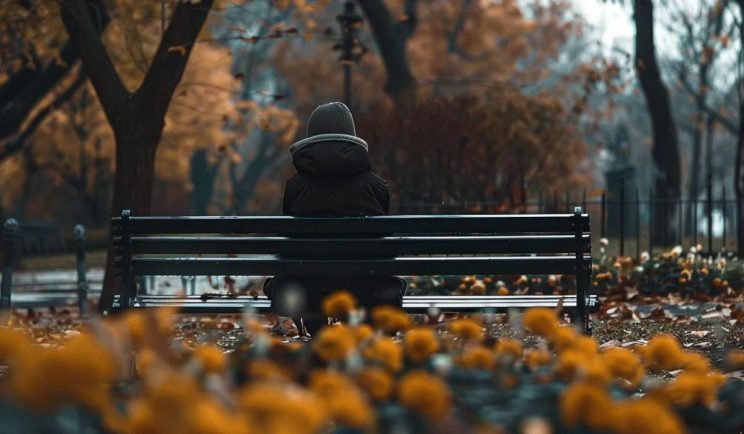 Person sitting alone on a park bench in autumn
