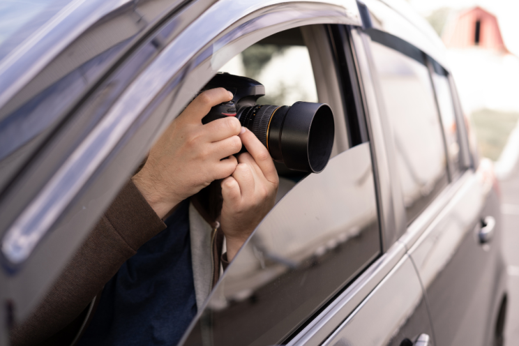 Private investigator taking photos through a car window using a DSLR camera with a zoom lens