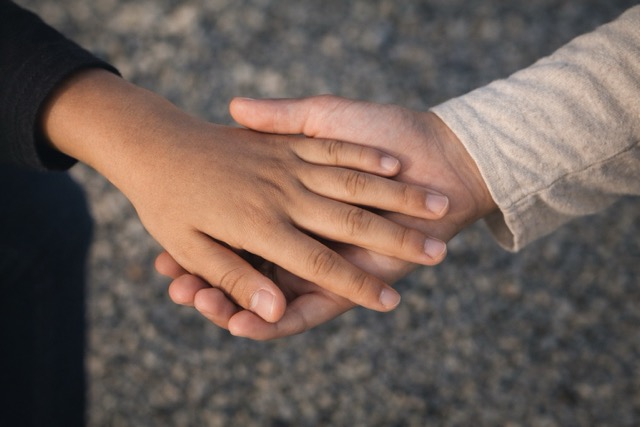Spousebusters service child custody. Close-up of two hands holding for reassurance, symbolising care and stability in a child custody case.
