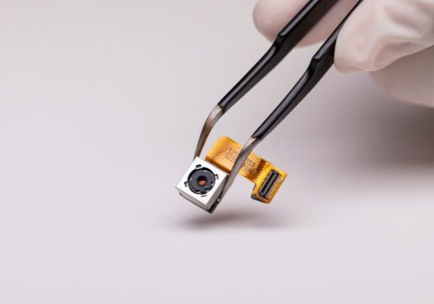 Close-up of a hidden camera component held by tweezers